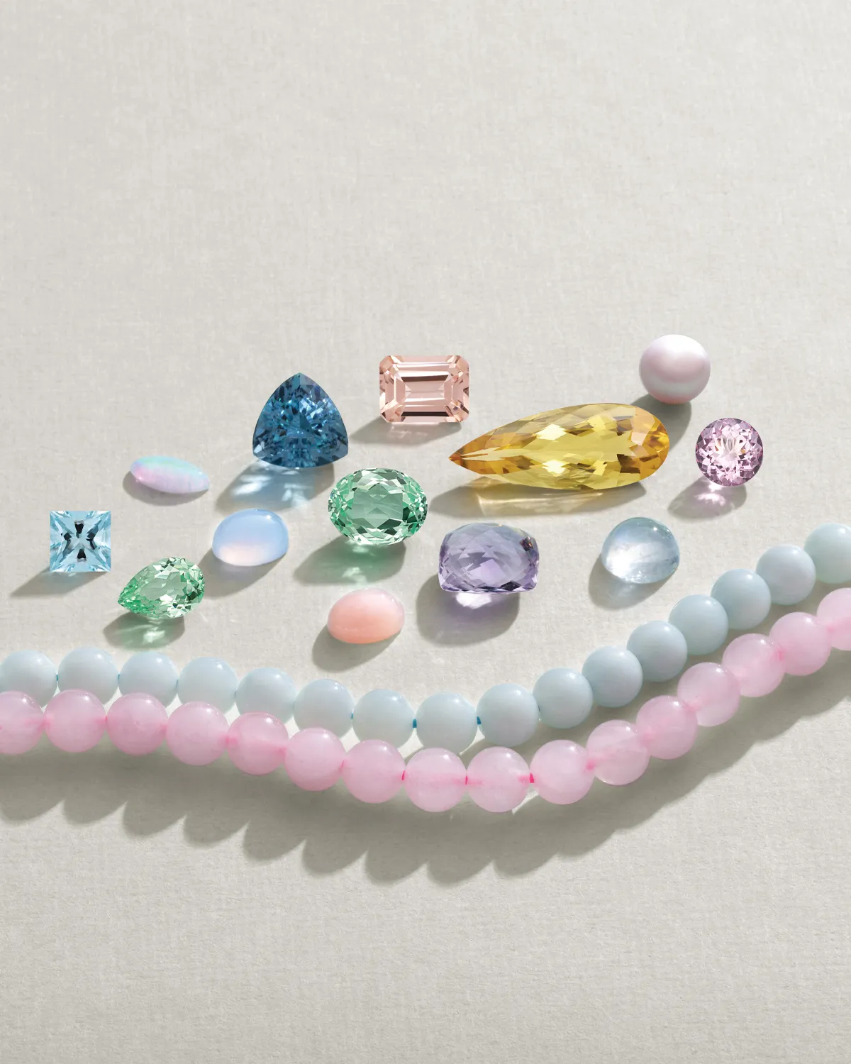 Colorful loose gemstones and beads displayed on a light background.