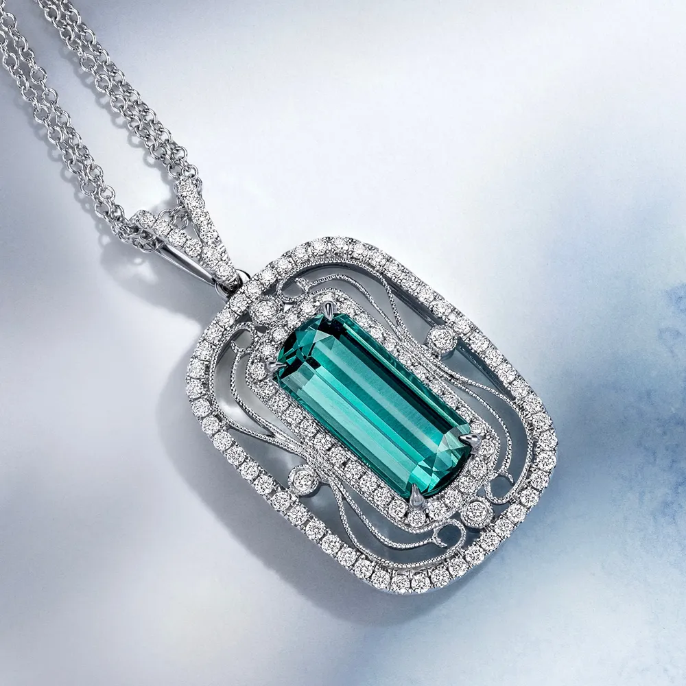 Elegant silver necklace featuring a large teal gemstone surrounded by sparkling diamonds.