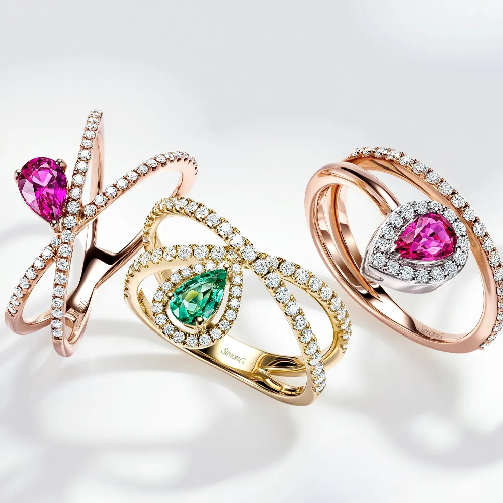 Close-up of multiple elegant rings featuring gemstones and diamonds on a hand.