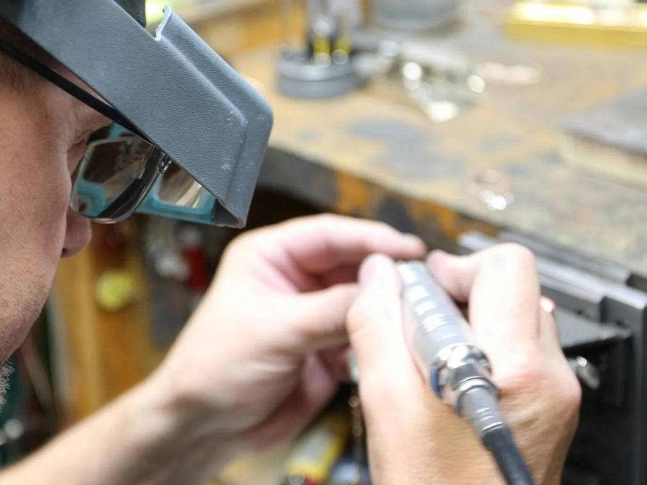 Close-up of a jeweler repairing a watch with precision tools. Visit Flora Gems for expert jewelry services.