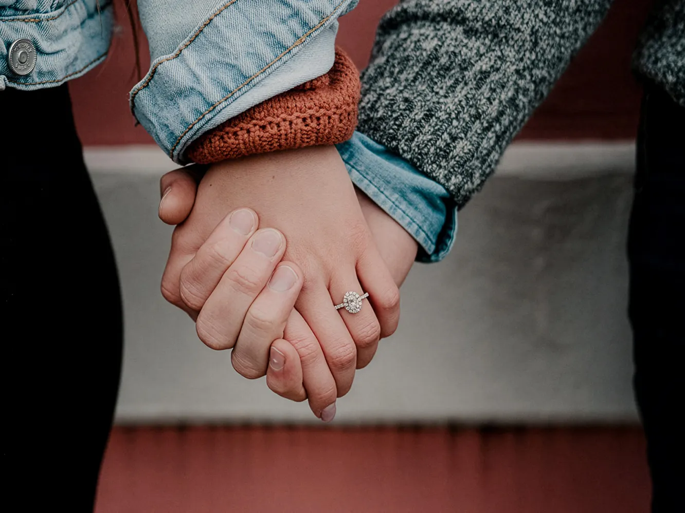 Couple holding hands, showcasing an engagement ring. Click to explore Flora Gems jewelry in Decatur & Champaign, IL.