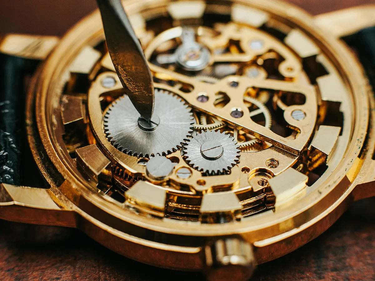 Close-up of a watch's intricate gears being repaired with a tool at Flora Gems, your trusted jewelry store in Decatur & Champaig