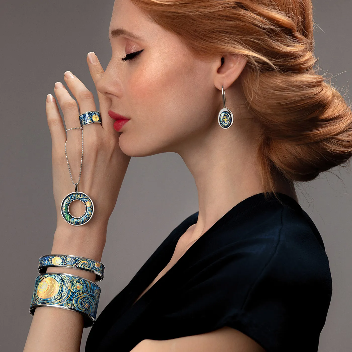 Jewellery displayed on light blue gift box, gold rings, loose diamonds and pearls scattered around with gold necklaces hanging. 