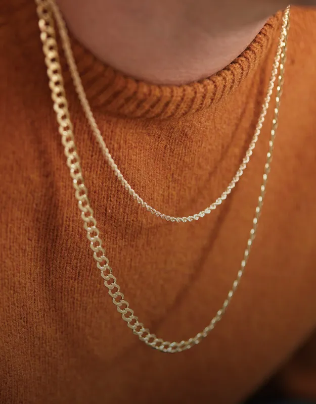 Gold layered necklaces worn by a model wearing an orange sweater.