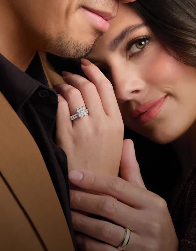 Engagement ring on a woman's hand, resting on her partner's shoulder.