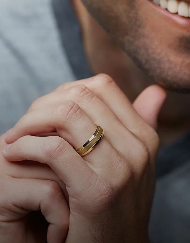 Man's hand showcasing a gold wedding band.