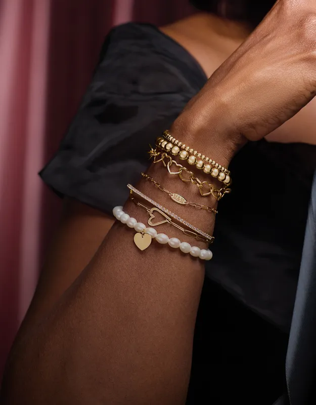 Elegant gold and pearl bracelets stacked on a wrist, showcasing various designs.