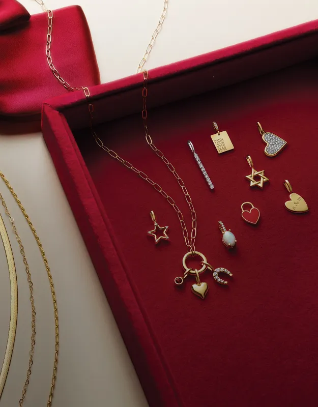 Gold charm necklaces and accessories displayed in a red box. Click to explore charms and accessories at Futer Bros Jewelers.