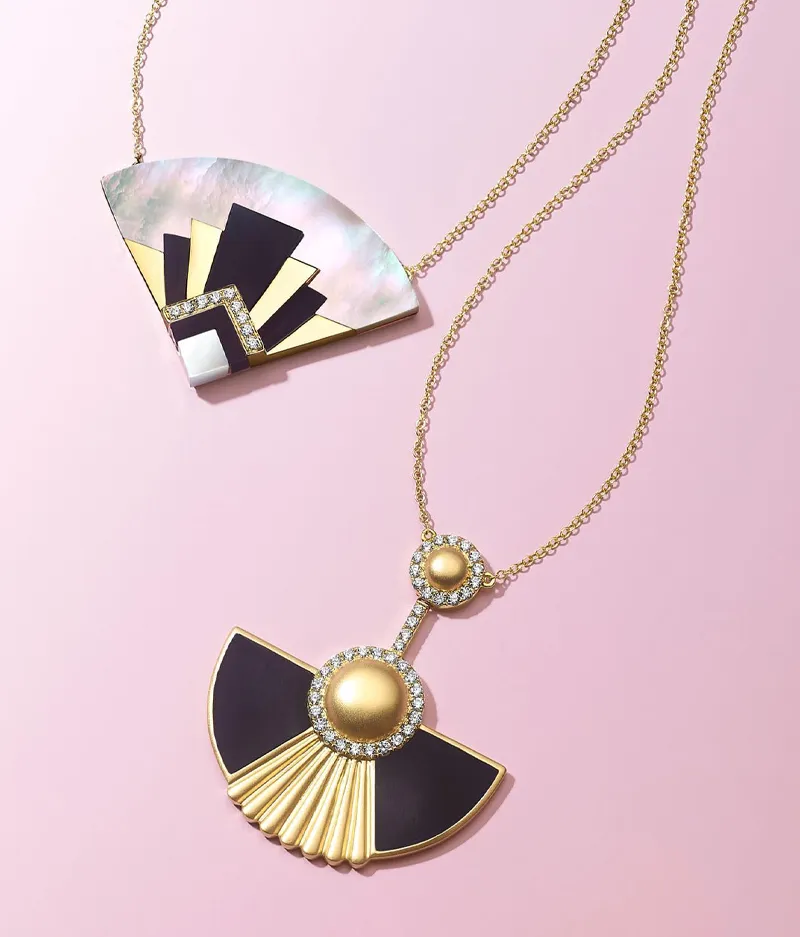 Two elegant fan-shaped necklaces, one with gold and black accents, the other with mother-of-pearl and gold details. Shop Now.