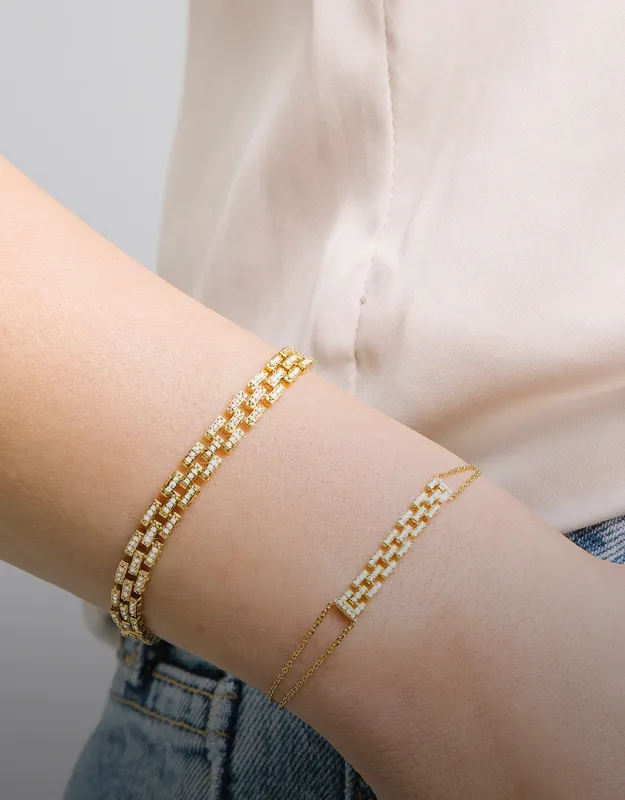 Elegant gold bracelets stacked on a wrist, showcasing various designs. Explore more at Futer Bros Jewelers.
