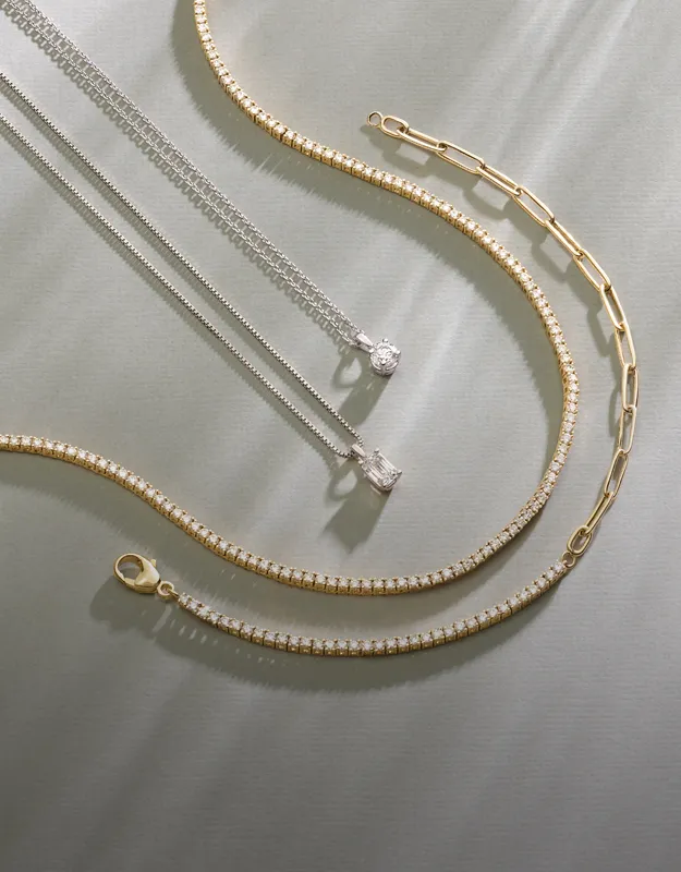 Layered gold and silver chains with pendants on a light background. Explore chains at Futer Bros Jewelers.