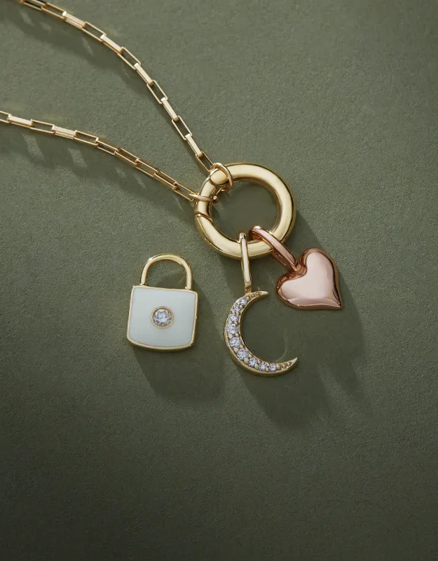 Gold necklace with lock, crescent, and heart charms on green background. Click to explore charms and accessories at Futer Bros J