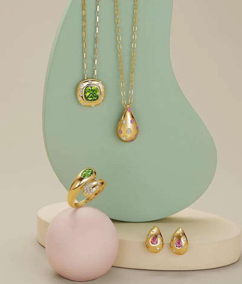 Elegant gold jewelry set with green and pink gemstones on display. Shop Now.