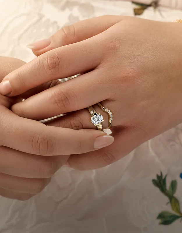 Hands with diamond engagement ring and gold band. Explore engagement rings.