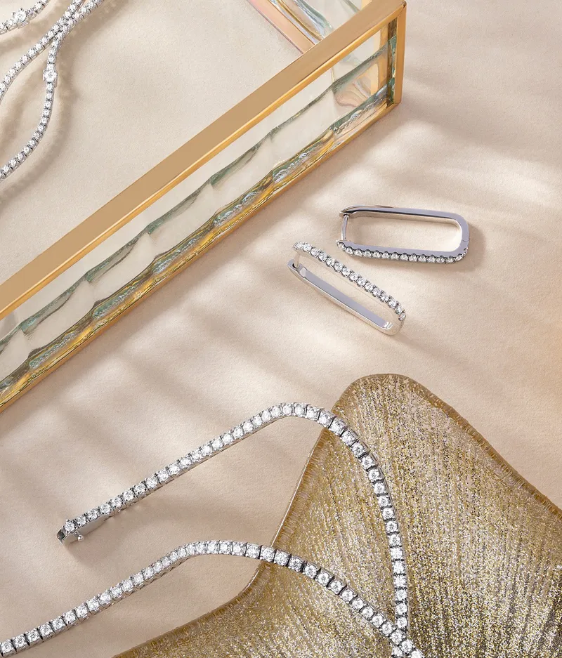 Elegant diamond necklace and earrings on a textured surface. Click to Shop Now at Futer Bros Jewelers.