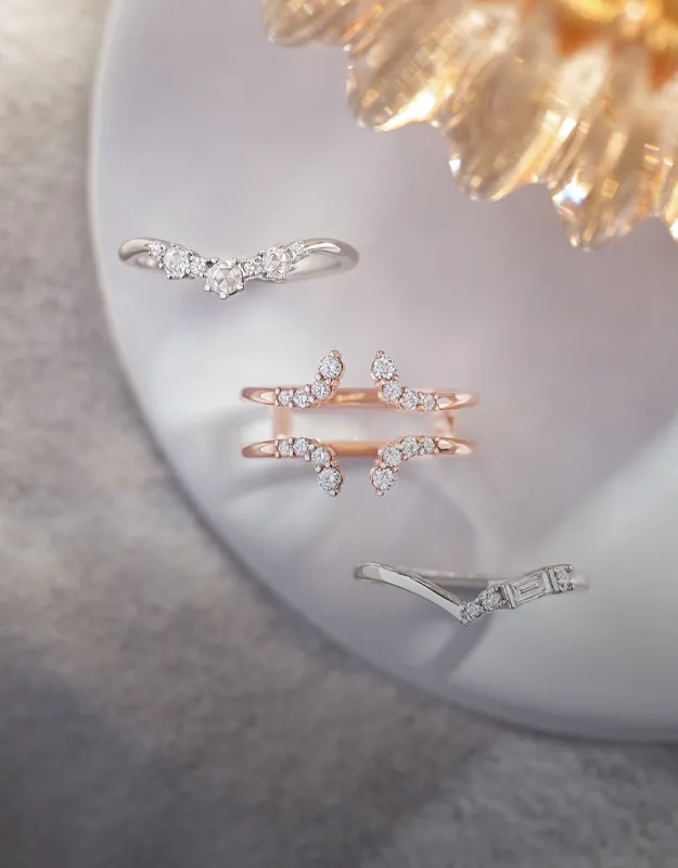 Three elegant women's wedding bands with sparkling diamonds on a soft background.