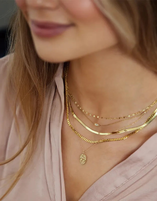Gold layered necklaces worn by a woman, showcasing elegant jewelry. Click to explore chains at Futer Bros Jewelers.