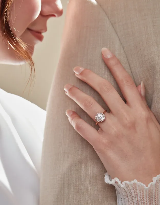 Engagement ring with a sparkling stone, hand resting on a partner's shoulder. Explore more at Futer Bros Jewelers.