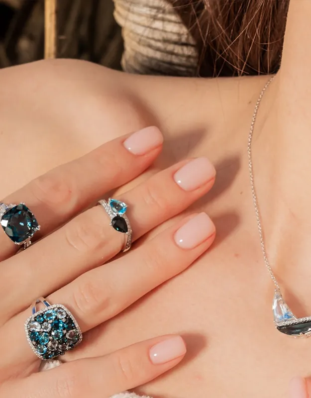 Elegant rings with blue gemstones and silver settings on a woman's hand. Click to explore more rings at Futer Bros Jewelers.