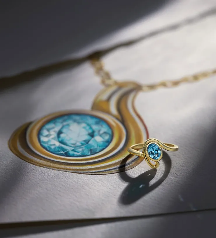 Gold ring with blue gemstone on a sketch of a matching jewelry design.