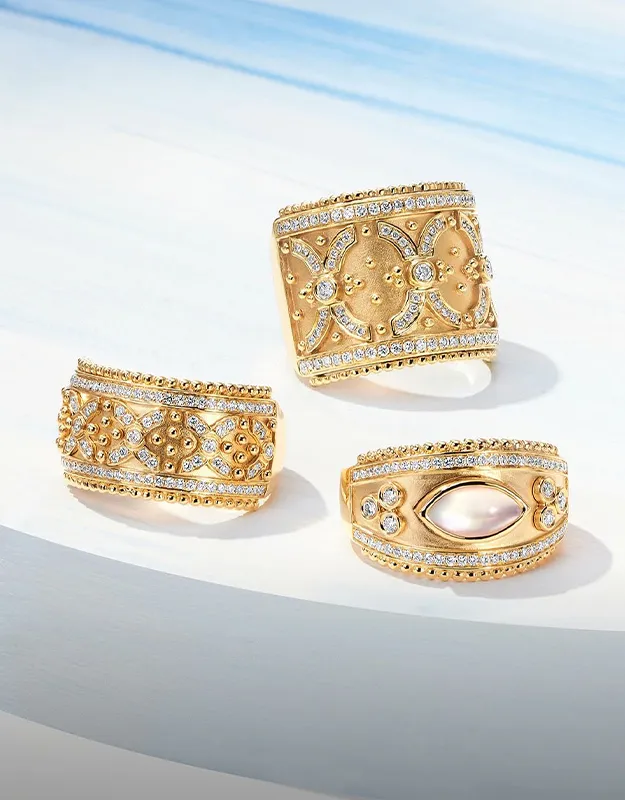 Three ornate gold rings with diamond accents on a light background.