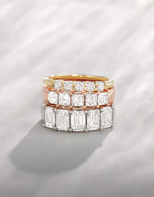 Three elegant women's wedding bands with sparkling diamonds on a soft background.