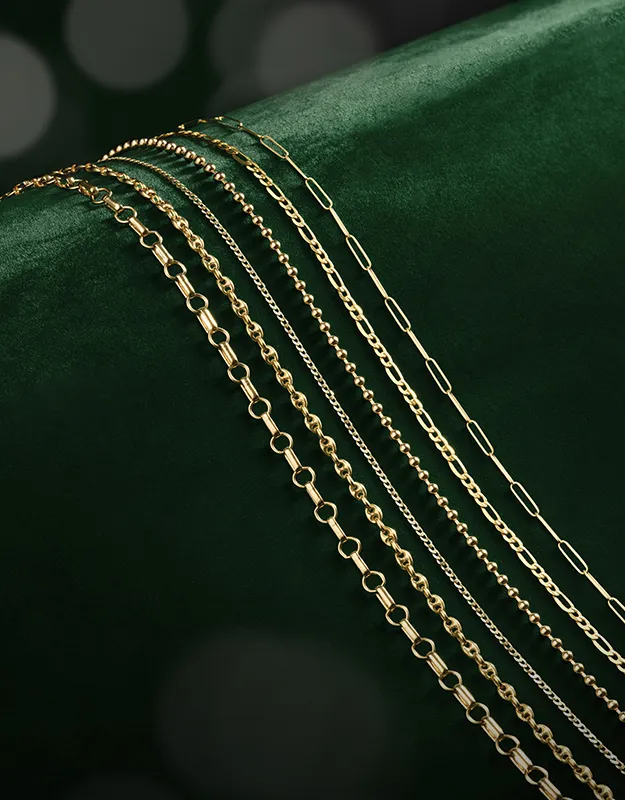 Layered gold chains with various link styles on a dark green background.