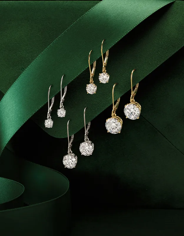 Elegant gold and silver earrings with diamonds on a dark green background.