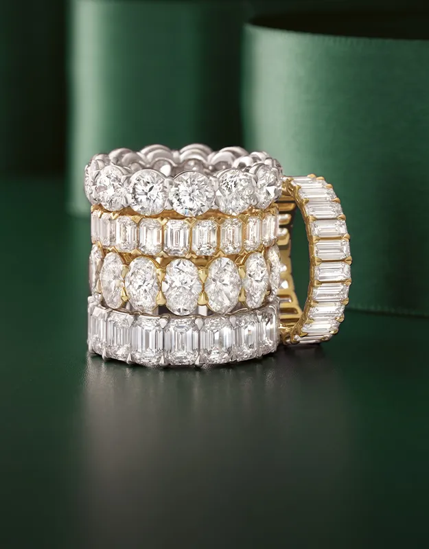 Three elegant women's wedding bands with sparkling diamonds on a green background.