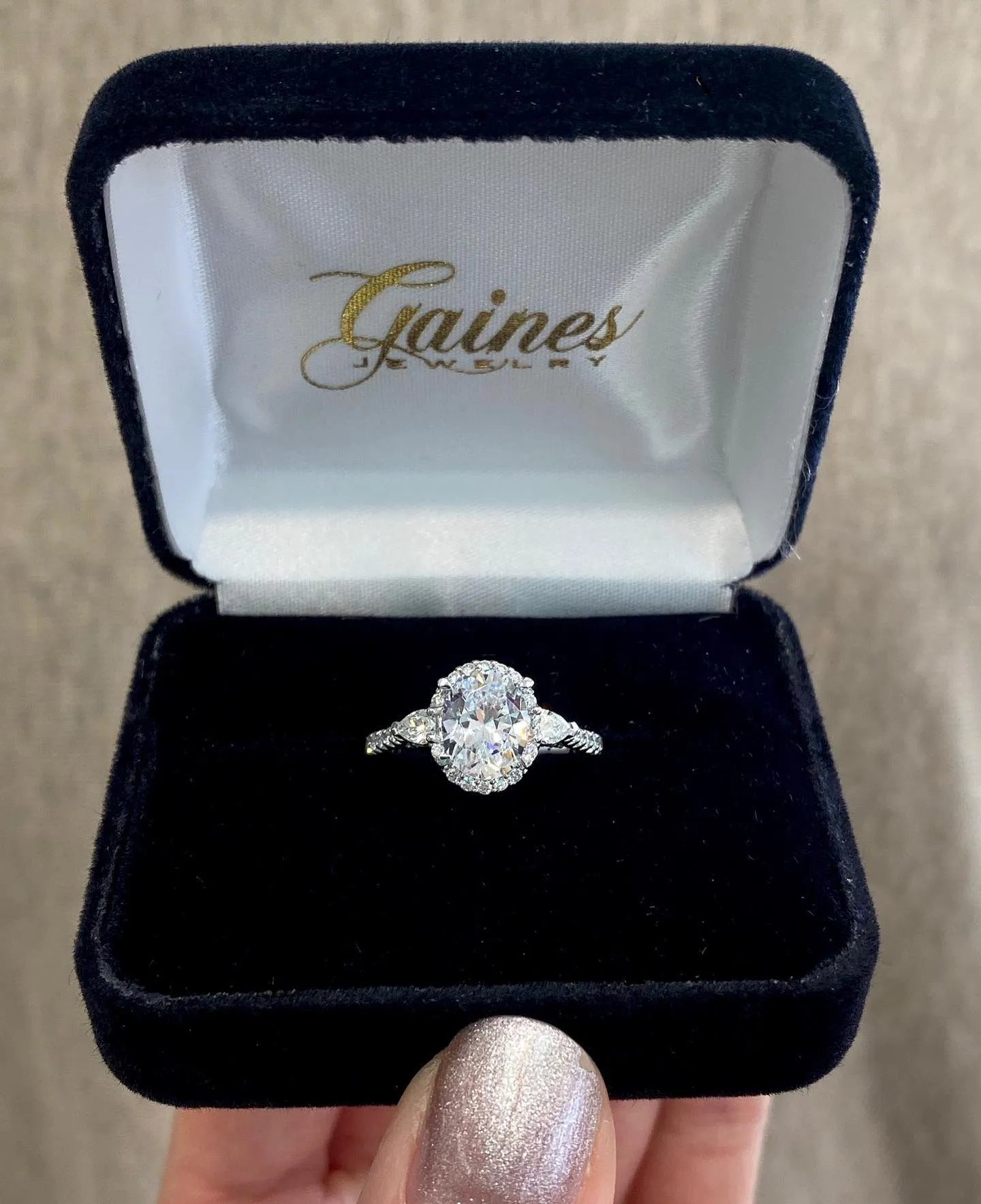 Jewelry design sketch of a ring with a large central stone and side details, pencil and marker nearby.