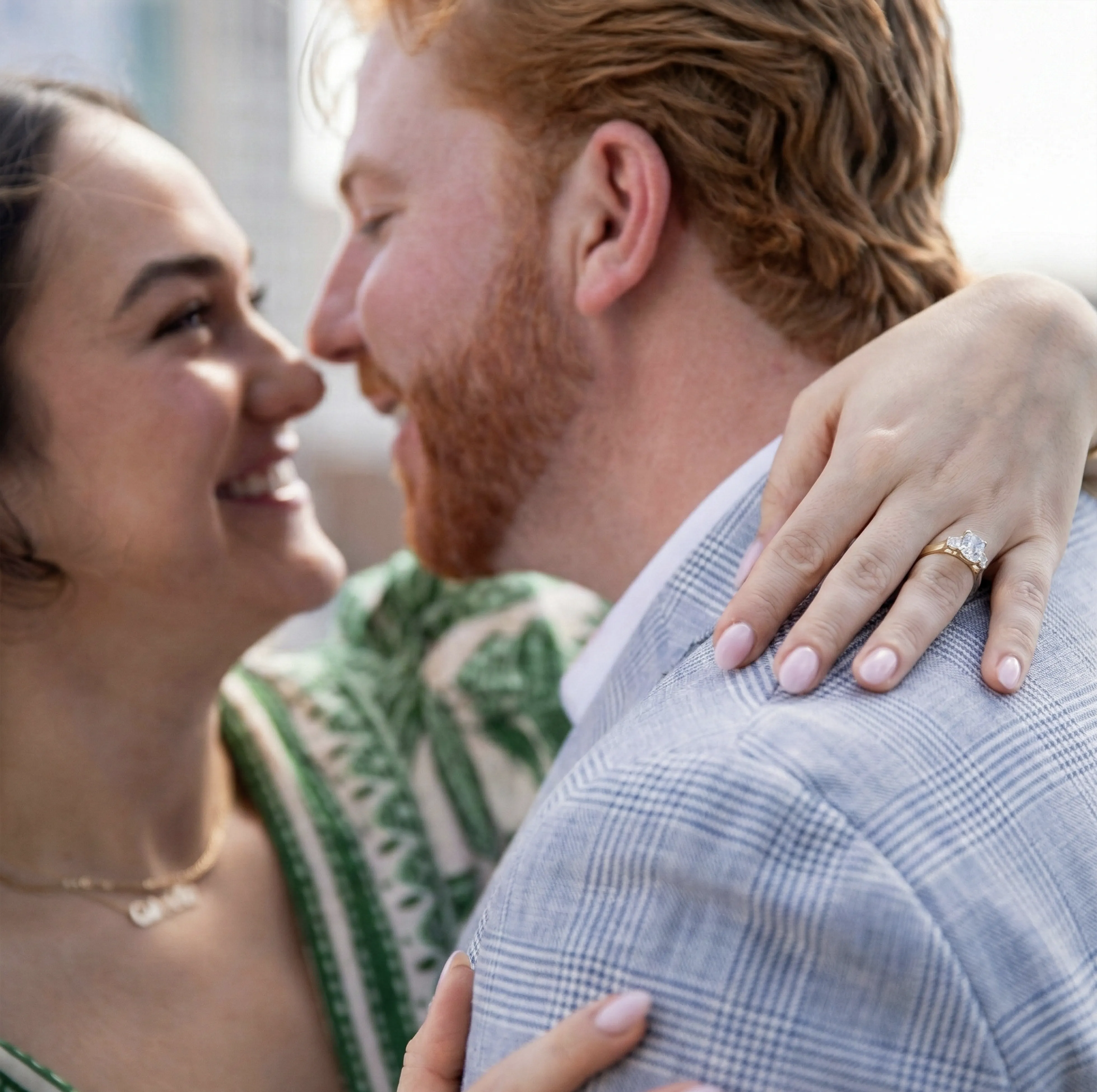 Hands holding, one wearing an emerald-cut diamond ring.