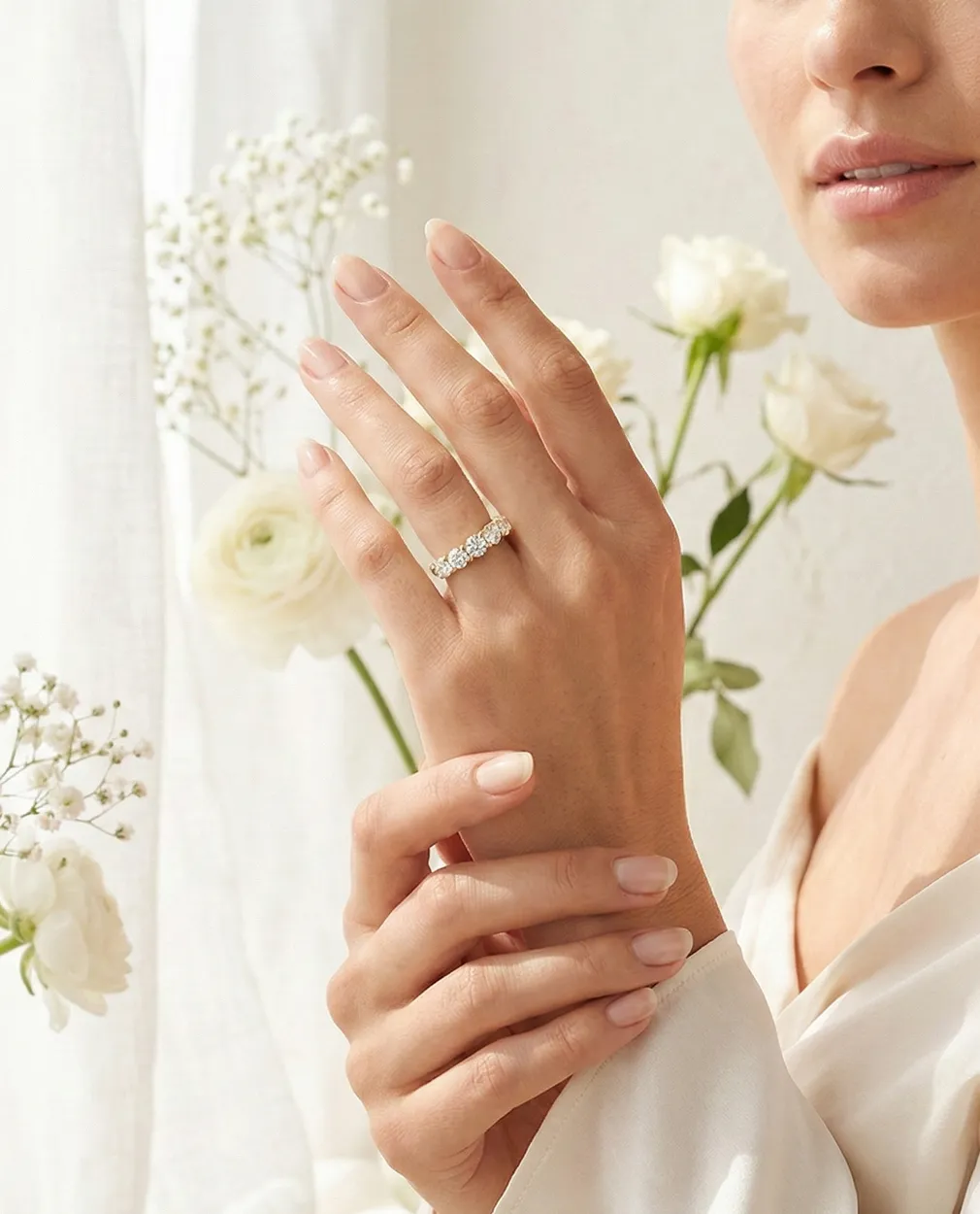 A hand with a diamond ring, surrounded by white flowers.