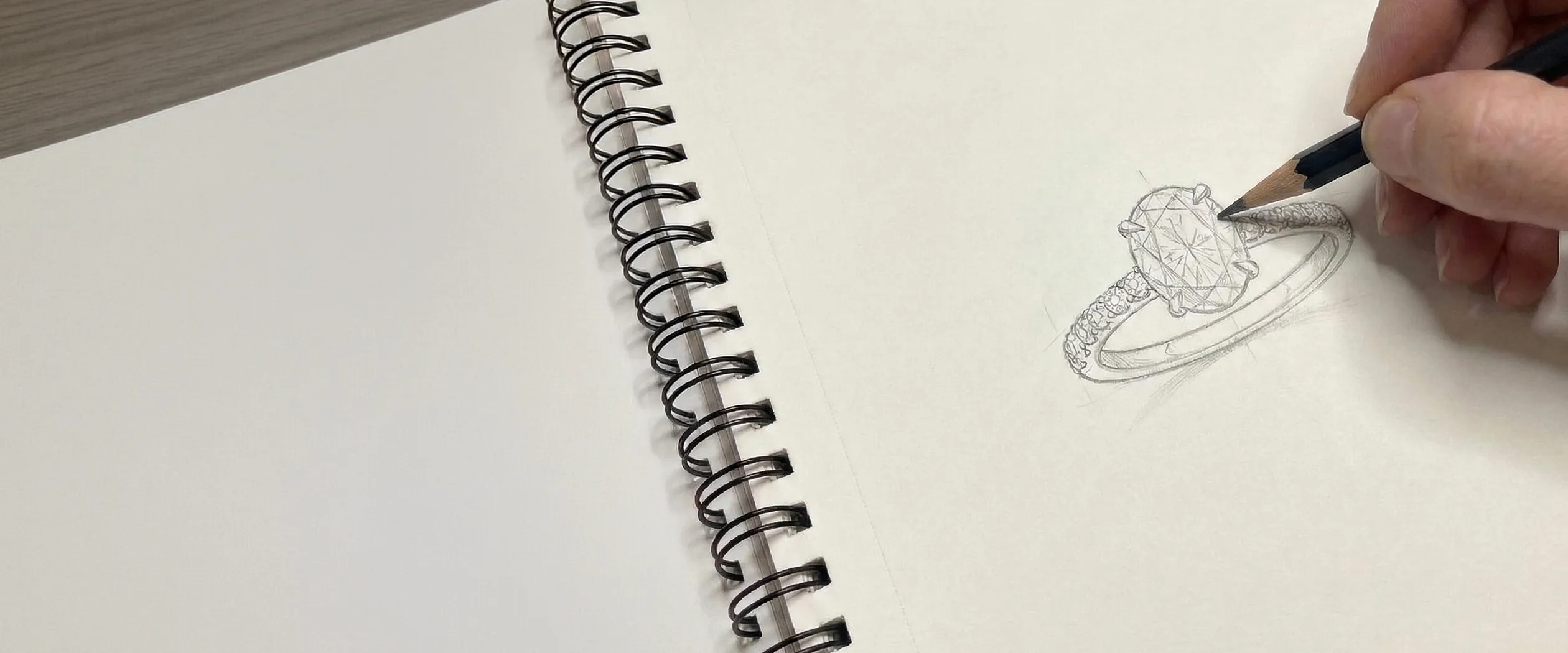 Sketch of a diamond ring being drawn in a spiral notebook.