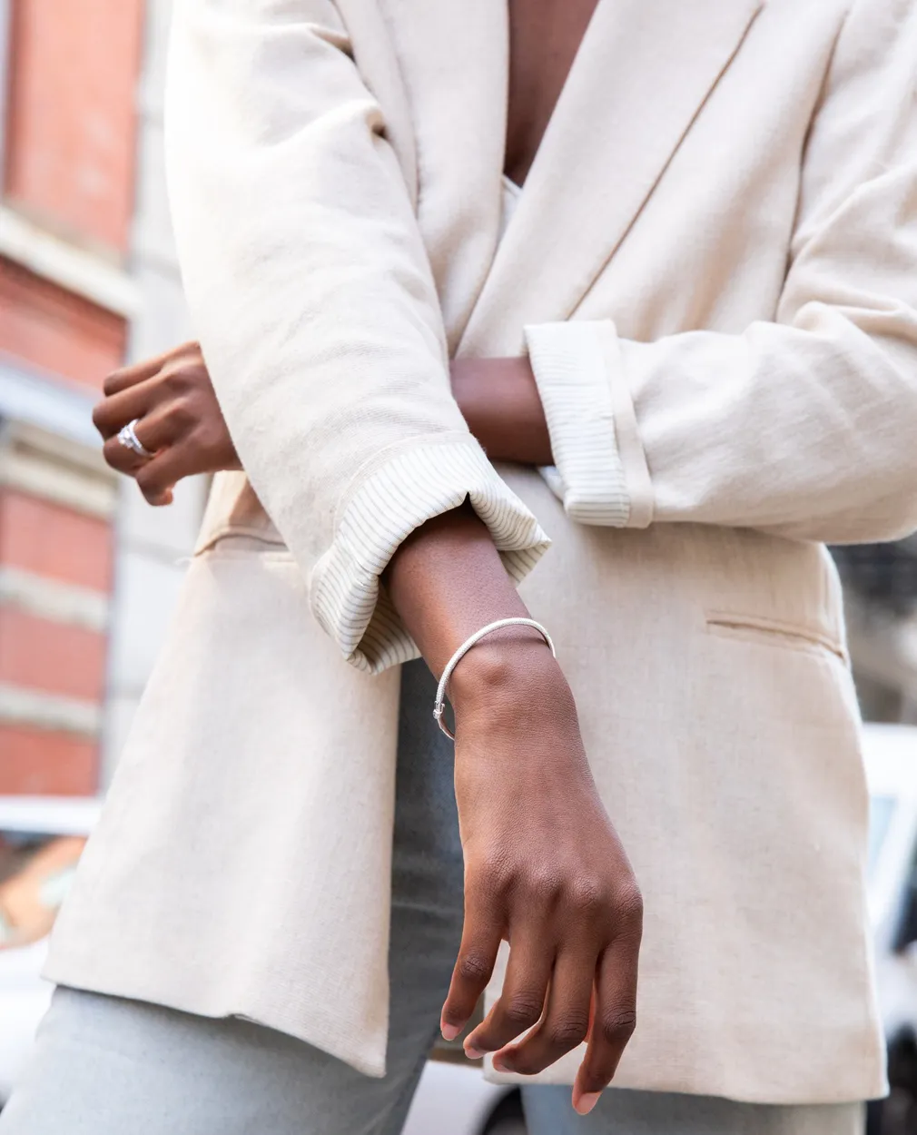 Woman in a beige blazer with a silver bracelet.