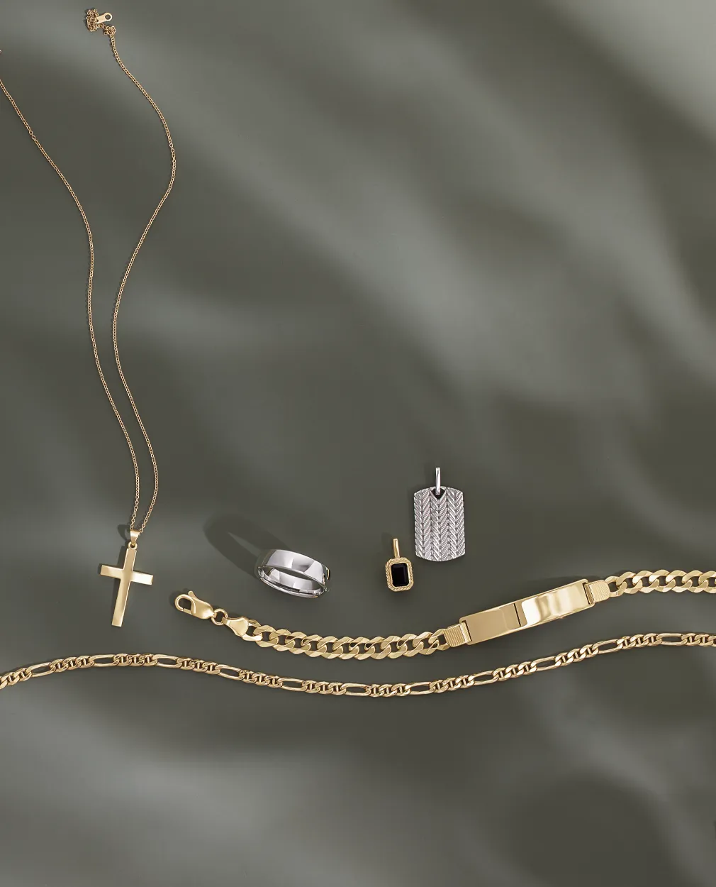 Men's jewelry collection with necklaces, rings, and bracelets on a green background.