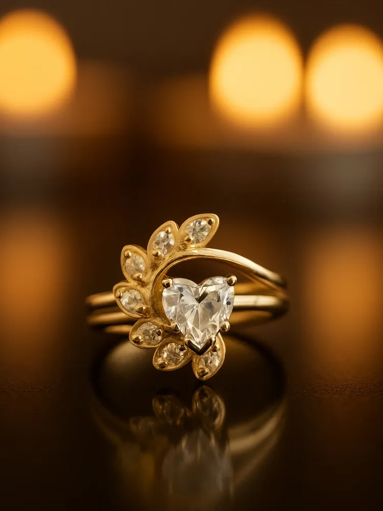 Heart-shaped diamond ring with gold band and leaf design, set against a warm, blurred background.