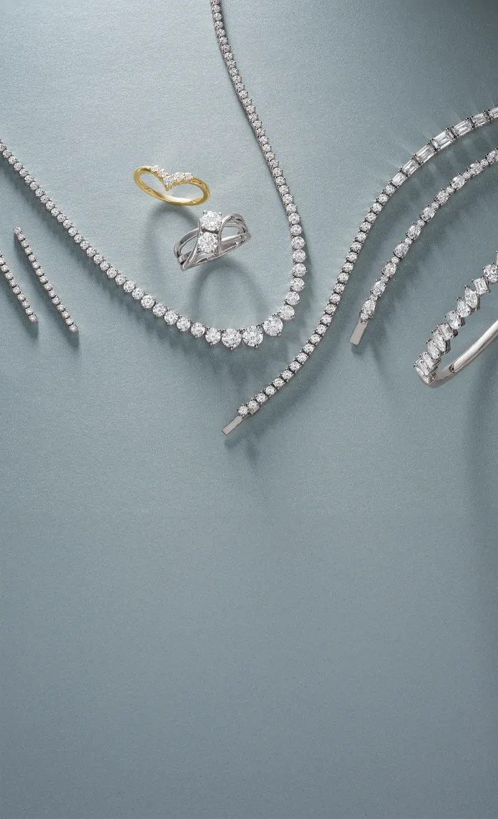 Elegant display of lab-grown diamond jewelry including rings and bracelets on a soft blue background.
