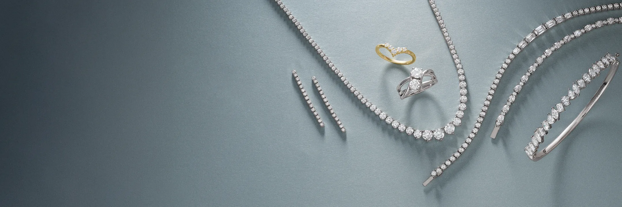 Elegant display of lab-grown diamond jewelry including rings and bracelets on a soft blue background.