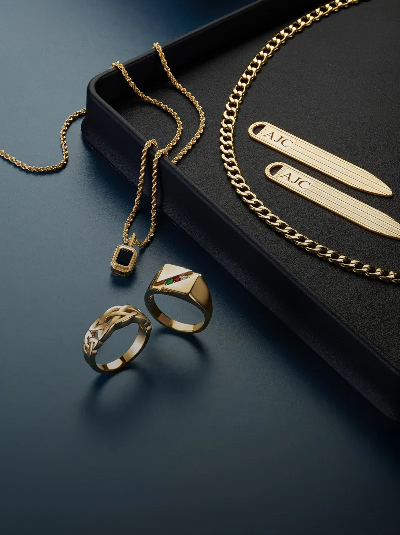 Gold jewelry display featuring rings, chains, and a pendant.