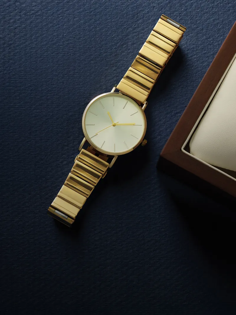 Gold watch with a minimalist design on a dark blue background.