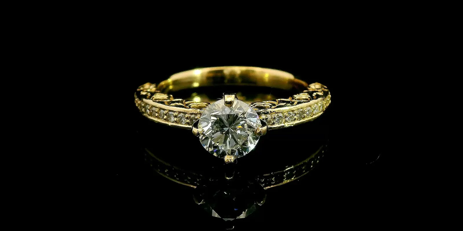 Elegant gold engagement ring with a large diamond centerpiece and intricate band design, reflecting light beautifully.