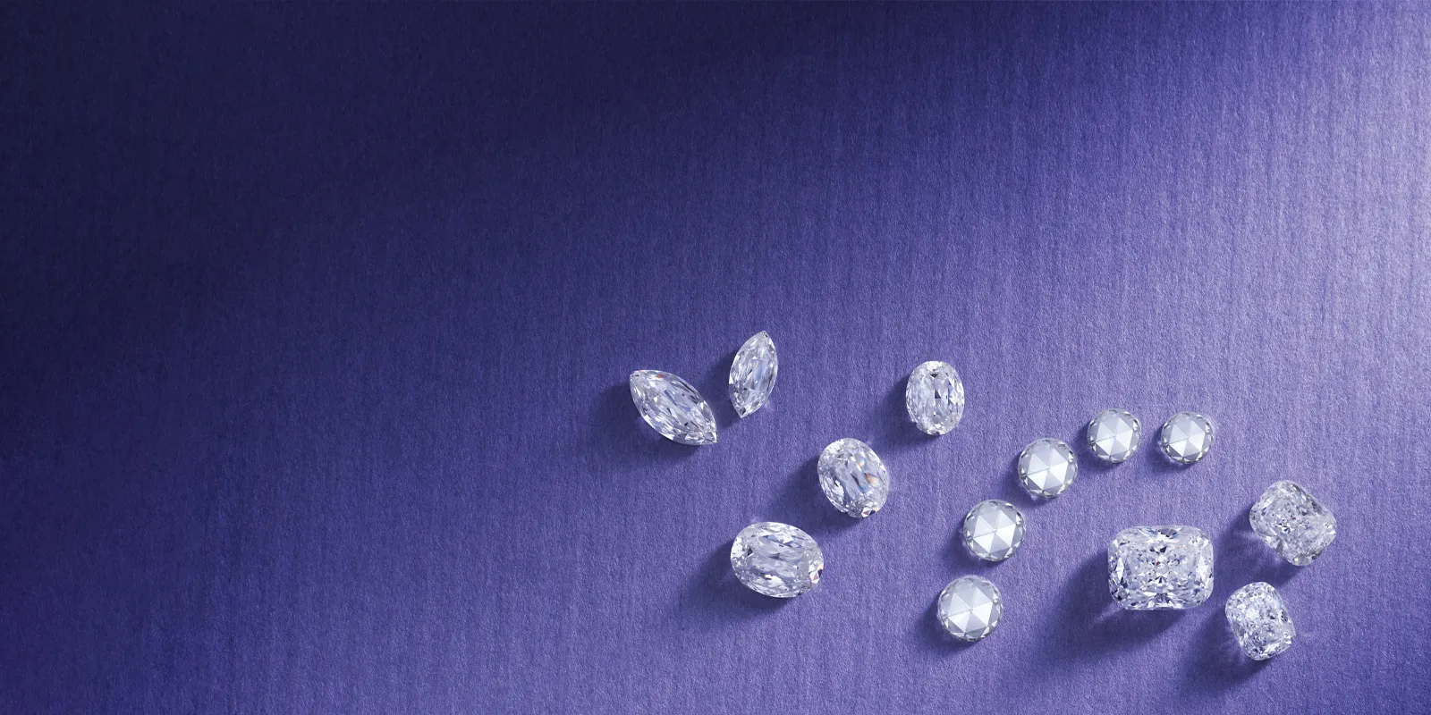 Loose diamonds arranged on a purple background, showcasing various cuts and shapes.