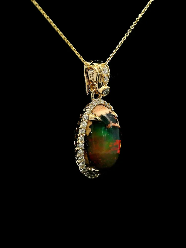 Gold pendant with a colorful opal and diamond accents, displayed on a black background.
