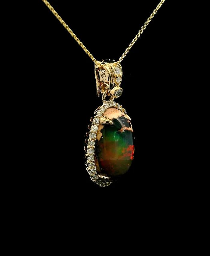 Gold pendant with a colorful opal and diamond accents, displayed on a black background.