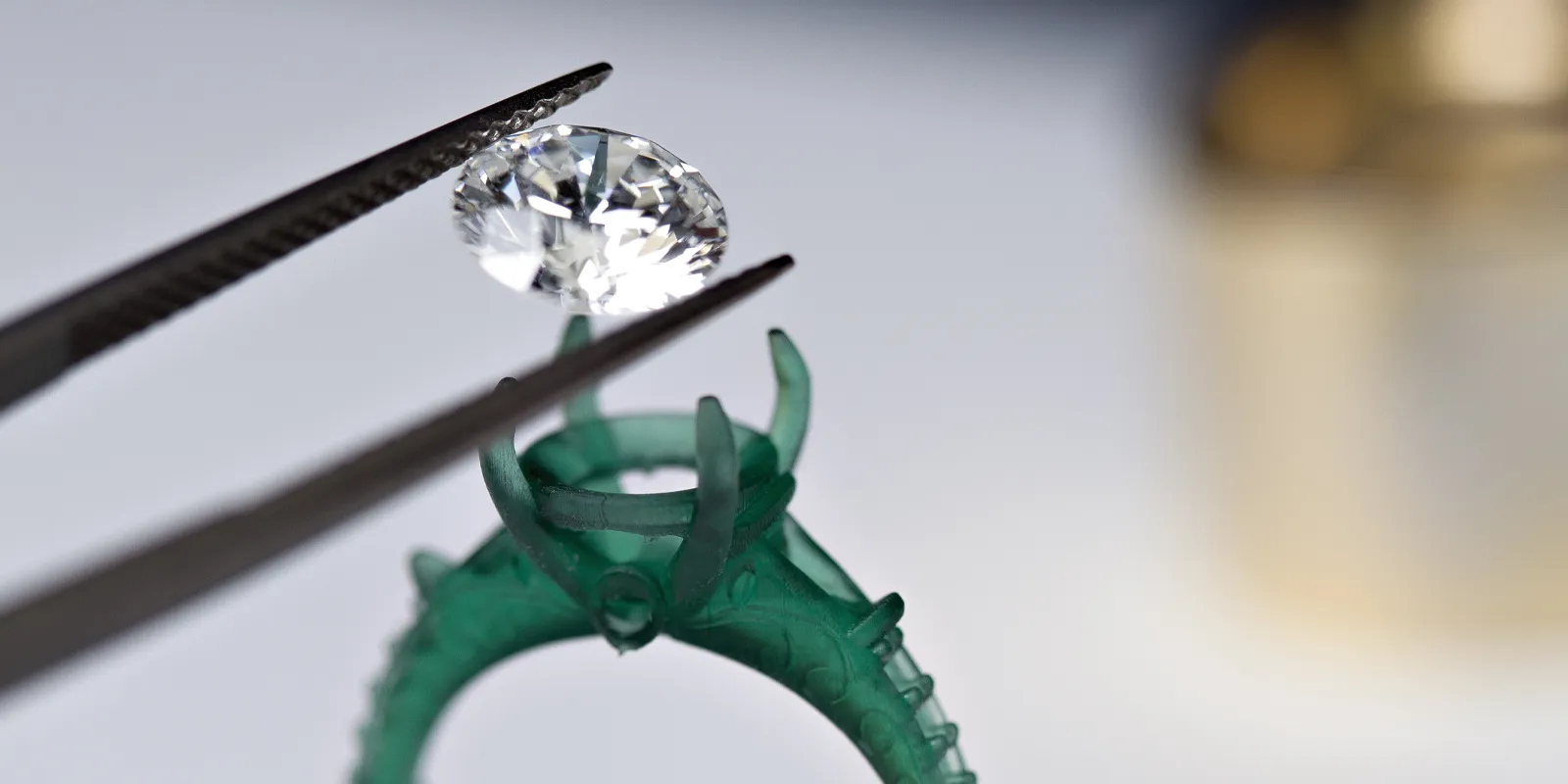 A diamond being placed into a green ring setting with tweezers, showcasing jewelry craftsmanship.