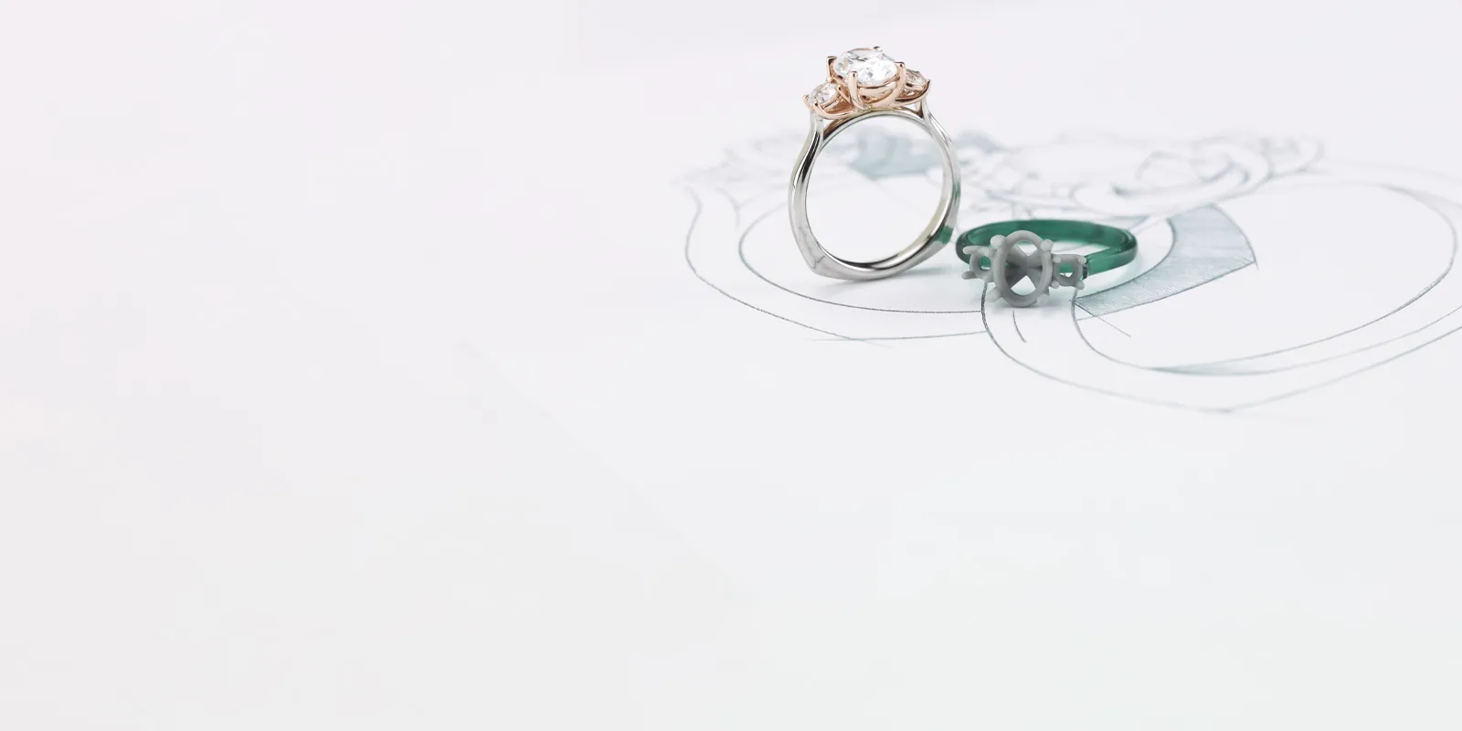 Elegant engagement ring and green band on a sketch background.