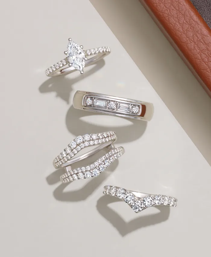 Five elegant diamond rings displayed on a neutral background, showcasing various styles and designs.