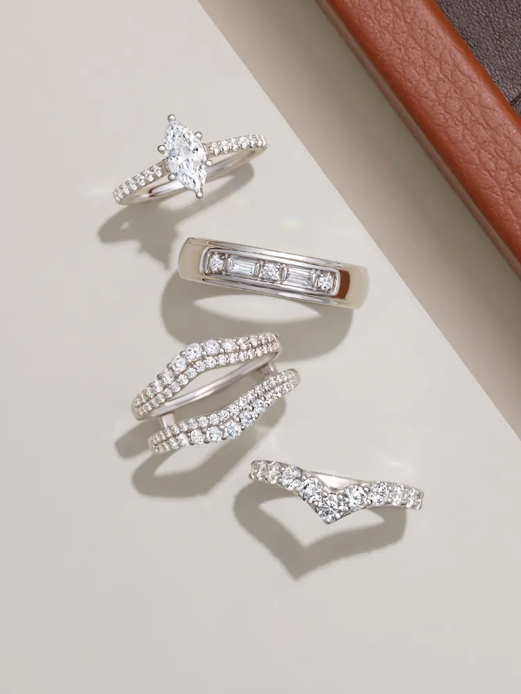 Five elegant diamond rings displayed on a neutral background, showcasing various styles and designs.