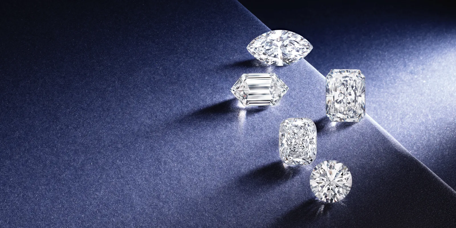 Five sparkling diamonds of various cuts on a dark blue background, showcasing Geneva Jewelry's fine selection.