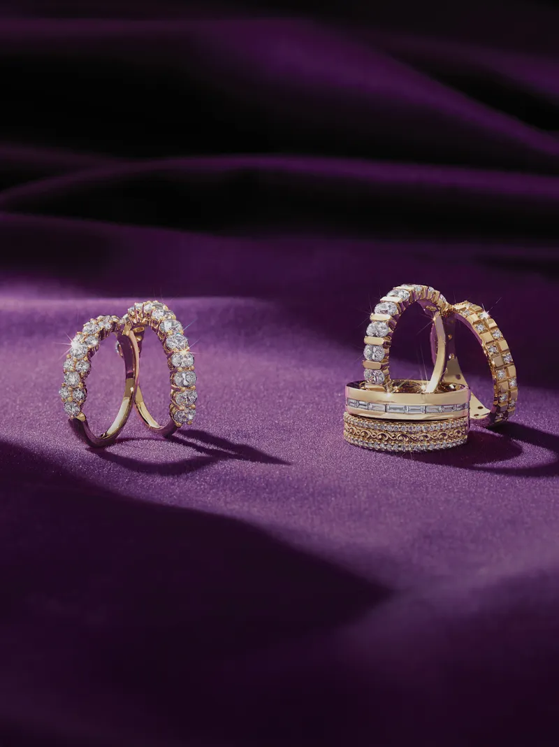 Elegant diamond rings displayed on a purple fabric backdrop.